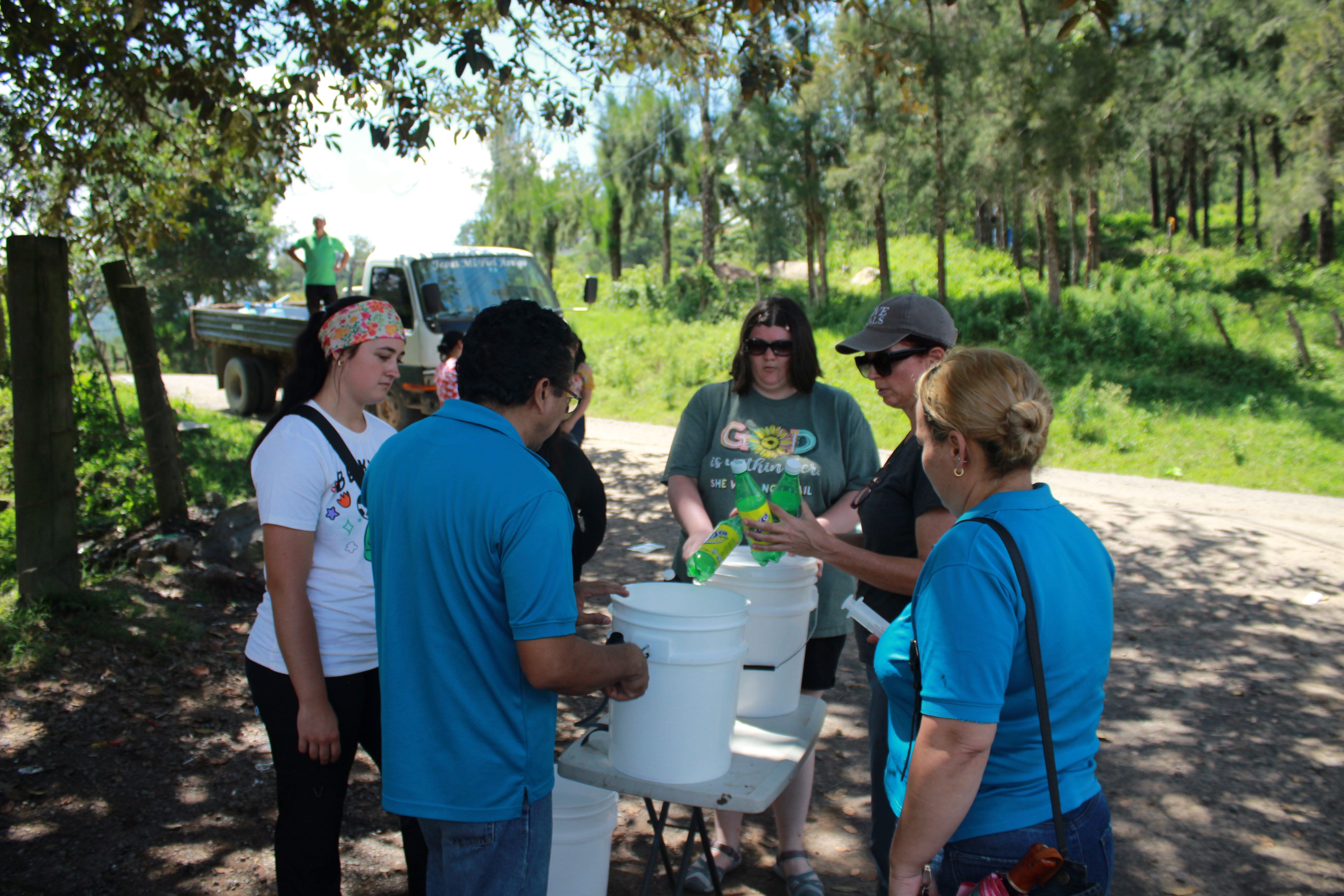 People standing outside examining buckets for water filtering