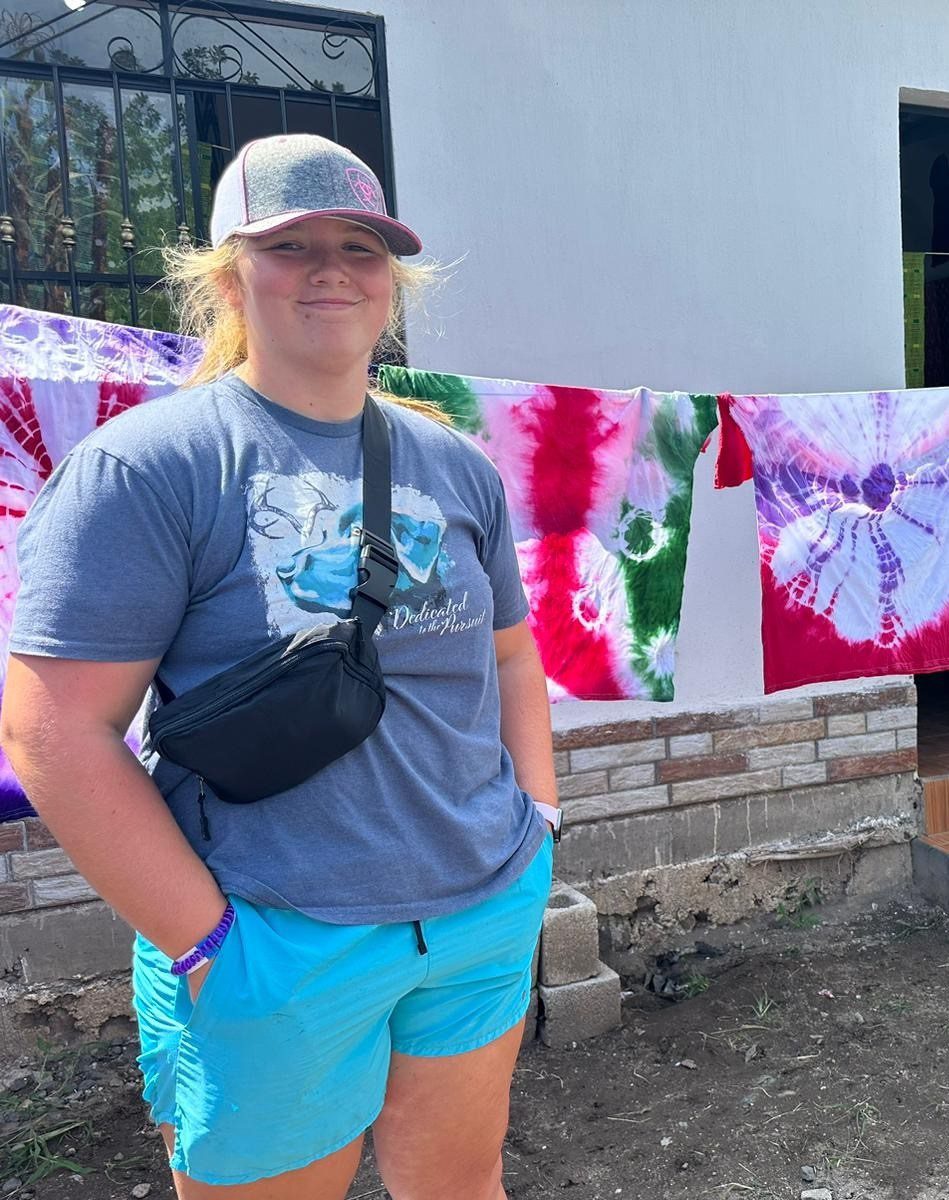 girls standing in front of tie dye shirts drying on line